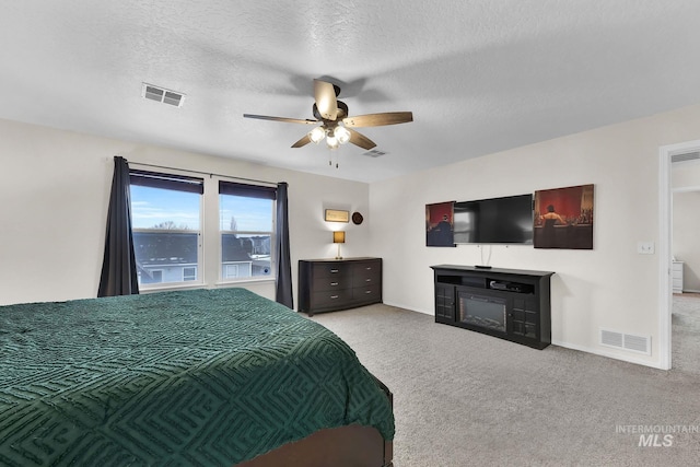 carpeted bedroom with ceiling fan and a textured ceiling