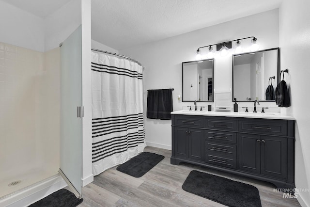 bathroom with hardwood / wood-style flooring, vanity, a textured ceiling, and walk in shower