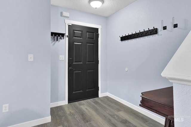 entryway with dark wood-type flooring and a textured ceiling