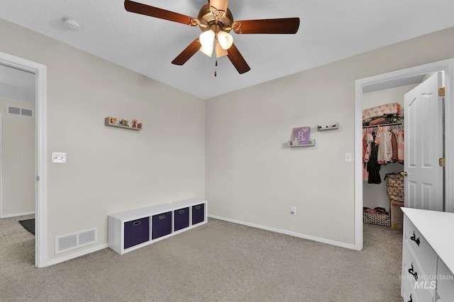 unfurnished bedroom with ceiling fan, a closet, a spacious closet, and light carpet