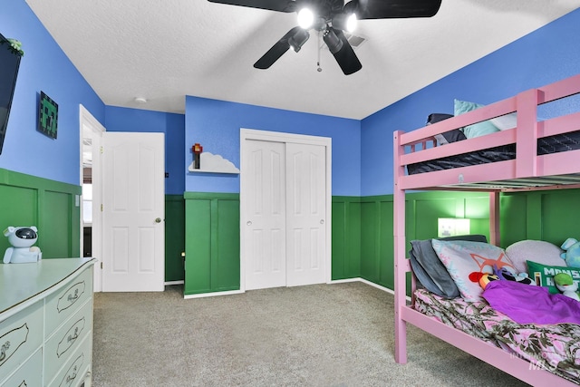 carpeted bedroom with ceiling fan, a closet, and a textured ceiling