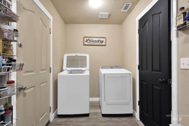 laundry area with hardwood / wood-style floors, washer and clothes dryer, and a textured ceiling