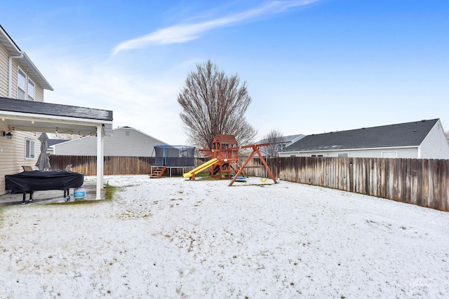 yard layered in snow with a playground and a trampoline