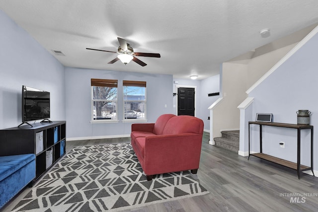 living room featuring ceiling fan, dark hardwood / wood-style floors, and a textured ceiling