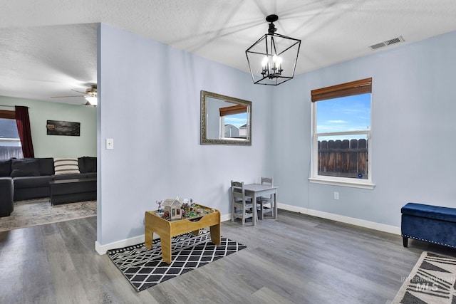 interior space with wood-type flooring, ceiling fan with notable chandelier, and a textured ceiling