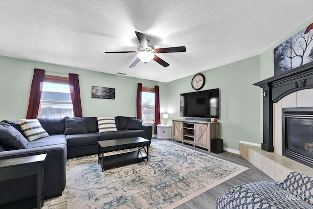 living room with a tiled fireplace, hardwood / wood-style flooring, a wealth of natural light, and ceiling fan