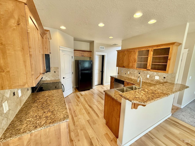 1241 W Ann Taylor St, Meridian, ID 83646 - kitchen with freestanding refrigerator, a sink, a peninsula, light wood-type flooring, and a breakfast bar area