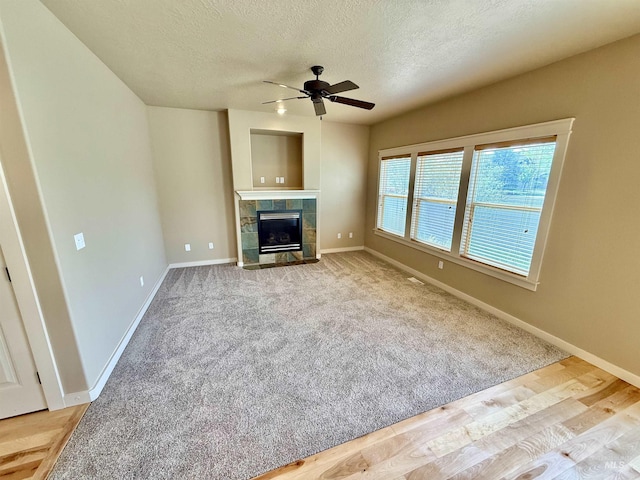 1241 W Ann Taylor St, Meridian, ID 83646 - unfurnished living room with ceiling fan, a textured ceiling, baseboards, a tile fireplace, and carpet flooring