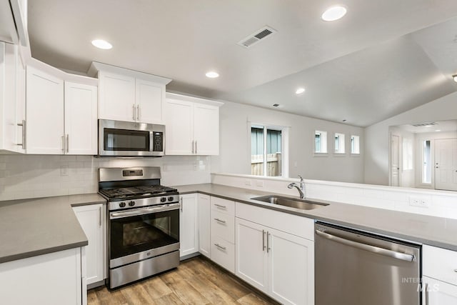 kitchen with white cabinets, appliances with stainless steel finishes, lofted ceiling, and sink