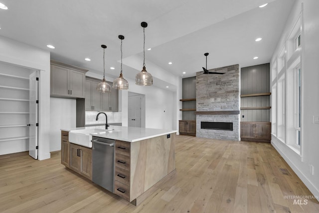 kitchen with a center island with sink, light hardwood / wood-style flooring, stainless steel dishwasher, and sink