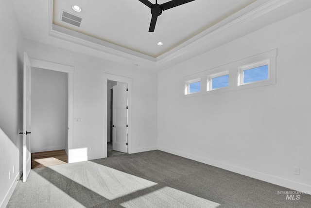 carpeted spare room with a tray ceiling, ceiling fan, and ornamental molding