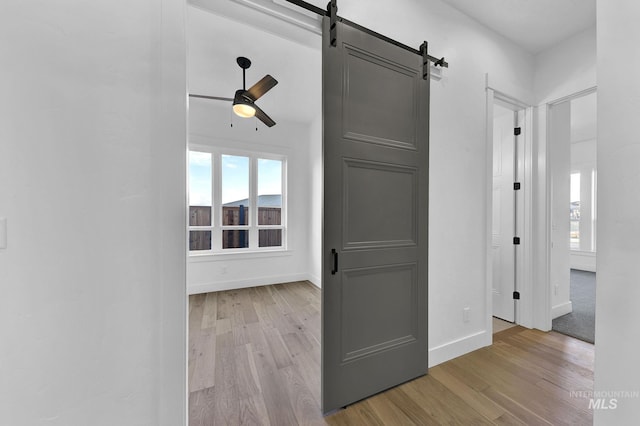 hallway with a barn door and light hardwood / wood-style flooring