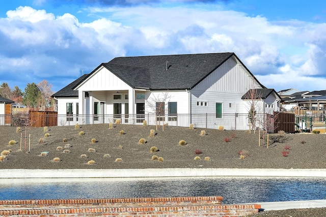 rear view of house with ceiling fan and a water view