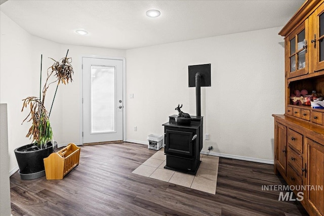 foyer entrance with a wood stove, baseboards, wood finished floors, and recessed lighting