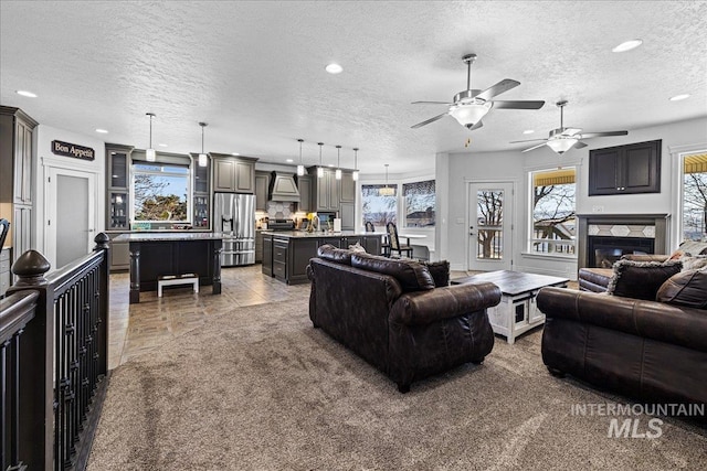 living room featuring light tile patterned floors, recessed lighting, light colored carpet, a glass covered fireplace, and a textured ceiling