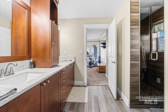 bathroom featuring double vanity, a stall shower, a sink, and a wealth of natural light