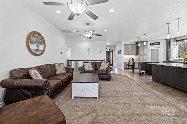 living room featuring a ceiling fan, recessed lighting, and a textured ceiling