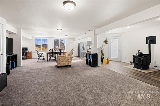 carpeted living area featuring a textured ceiling and a wood stove