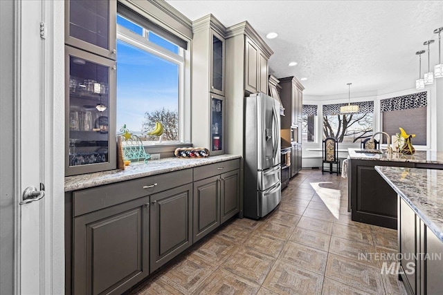 kitchen with glass insert cabinets, gray cabinets, stainless steel fridge, and decorative light fixtures