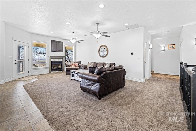 living room featuring visible vents, baseboards, a textured ceiling, a fireplace, and recessed lighting