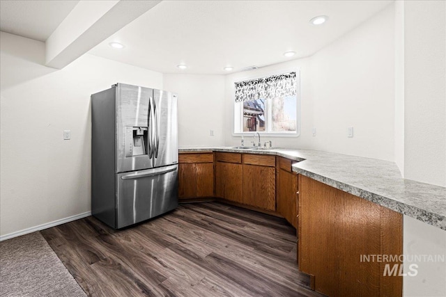 kitchen with dark wood-style floors, brown cabinetry, light countertops, and stainless steel fridge with ice dispenser