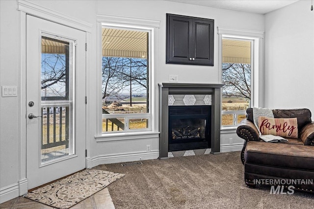 living room featuring visible vents, a stone fireplace, carpet flooring, and a wealth of natural light