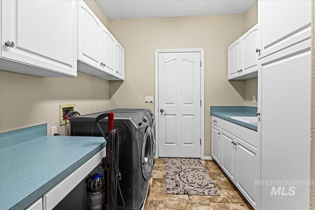 laundry area featuring a sink, baseboards, cabinet space, stone finish flooring, and washer and clothes dryer