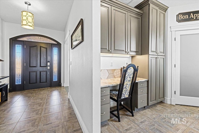 foyer featuring baseboards and built in study area