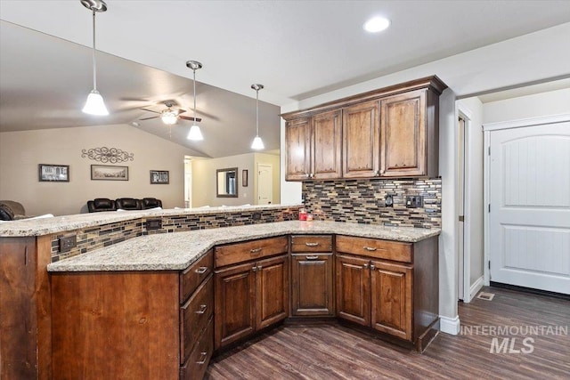 kitchen with backsplash, vaulted ceiling, dark wood-style floors, a peninsula, and hanging light fixtures