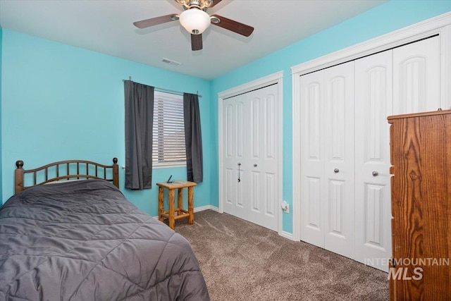 carpeted bedroom with visible vents, multiple closets, baseboards, and a ceiling fan