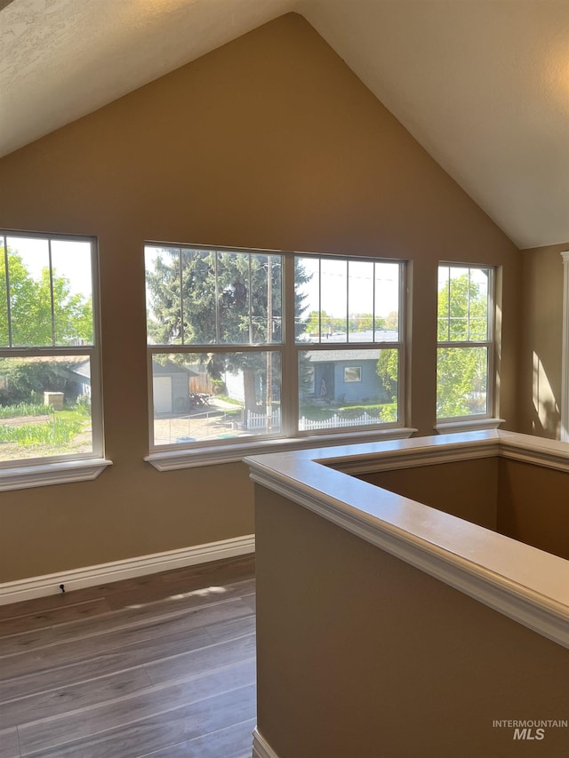 hallway featuring vaulted ceiling, wood finished floors, and baseboards