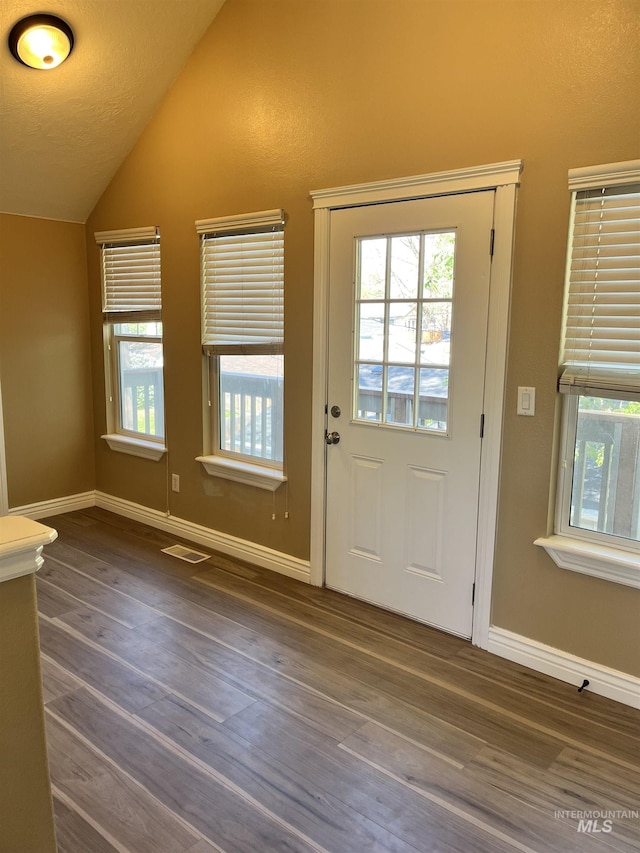 entryway with vaulted ceiling, wood finished floors, and baseboards