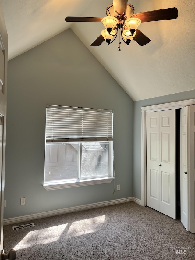 unfurnished bedroom with vaulted ceiling, carpet, a closet, a ceiling fan, and baseboards