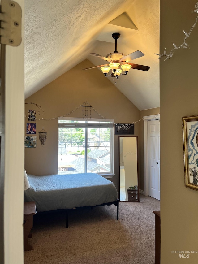 carpeted bedroom featuring vaulted ceiling, a textured ceiling, and a ceiling fan