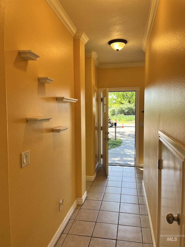 doorway to outside with ornamental molding, baseboards, and light tile patterned flooring