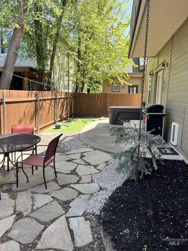 view of patio / terrace with a hot tub, a fenced backyard, outdoor dining space, and a grill