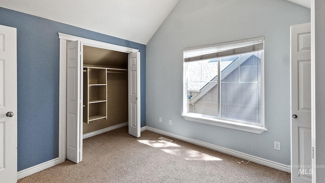 unfurnished bedroom featuring lofted ceiling, carpet flooring, a closet, and baseboards