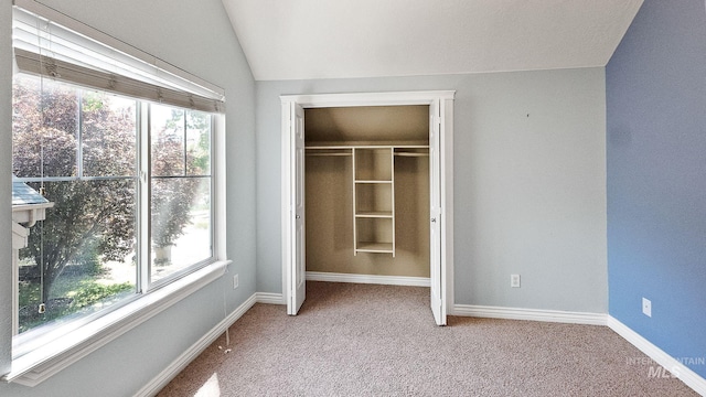 unfurnished bedroom featuring carpet, baseboards, vaulted ceiling, and a closet