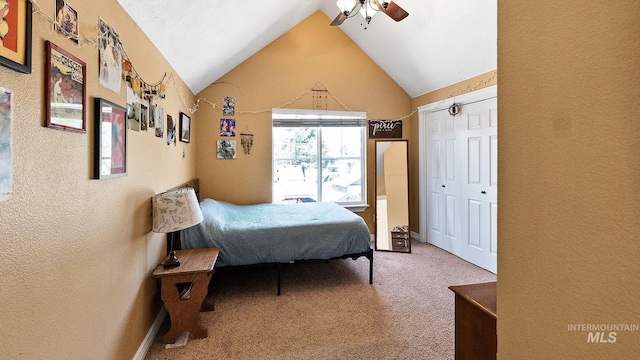 carpeted bedroom with a textured wall, vaulted ceiling, a closet, and ceiling fan