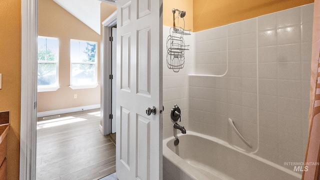bathroom featuring wood finished floors, vaulted ceiling, and shower / washtub combination