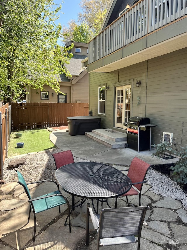 view of patio featuring a hot tub, outdoor dining area, grilling area, a balcony, and french doors