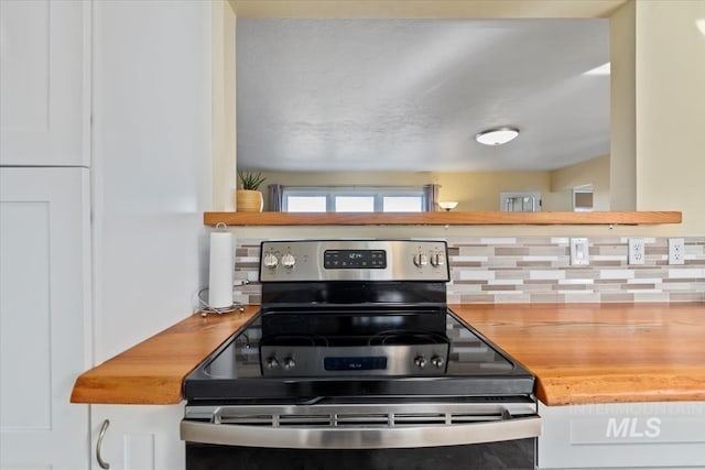 kitchen featuring white cabinets, wood counters, backsplash, and stainless steel range with electric cooktop