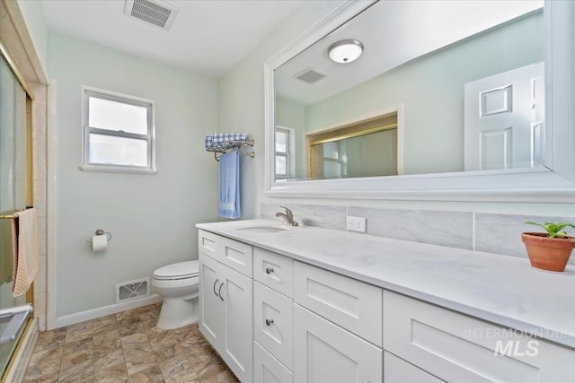 bathroom featuring vanity, toilet, a shower with shower door, and tasteful backsplash