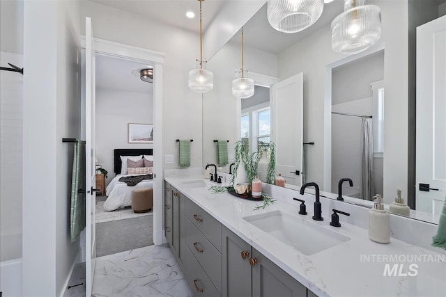 ensuite bathroom with marble finish floor, double vanity, a sink, and walk in shower