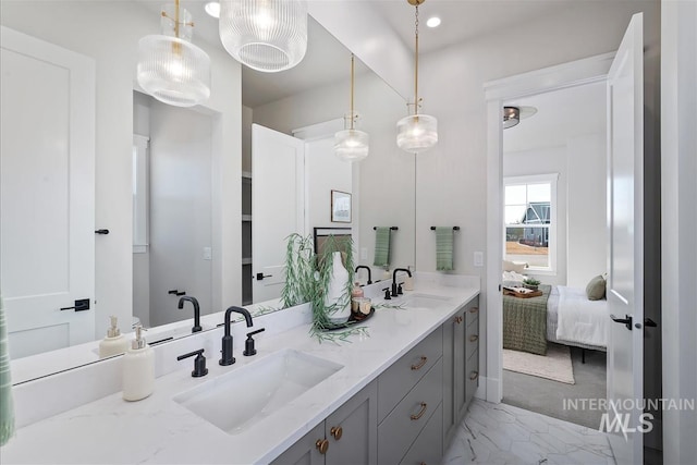 full bath featuring double vanity, marble finish floor, connected bathroom, and a sink