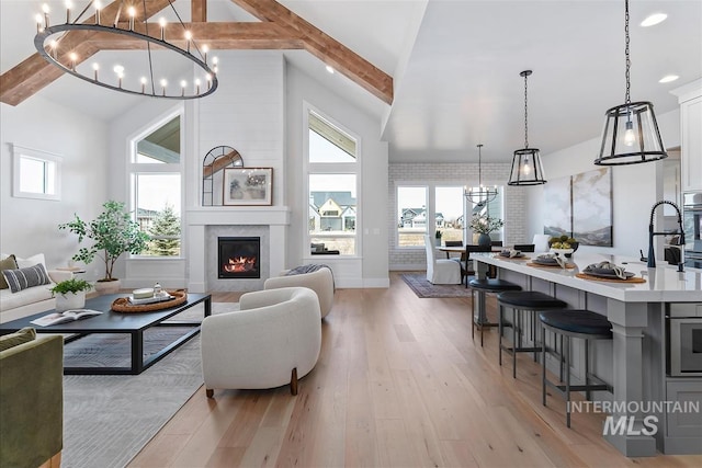 living room with a large fireplace, high vaulted ceiling, light wood finished floors, and beamed ceiling