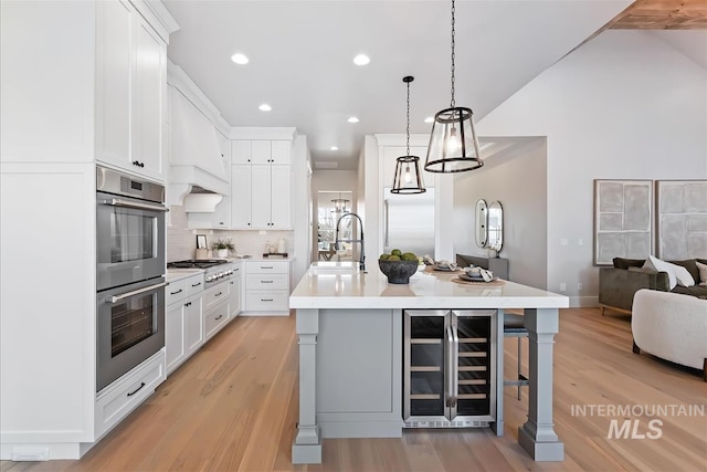 kitchen with wine cooler, stainless steel appliances, a sink, open floor plan, and light countertops