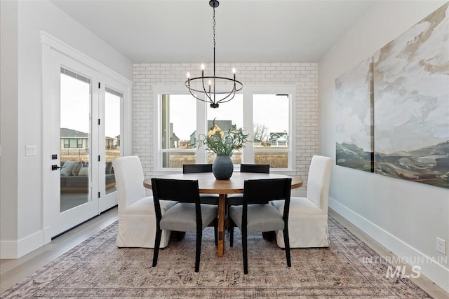 dining area with baseboards, brick wall, a chandelier, and a wealth of natural light