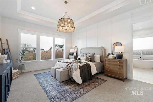 carpeted bedroom with a tray ceiling, visible vents, a decorative wall, and multiple windows