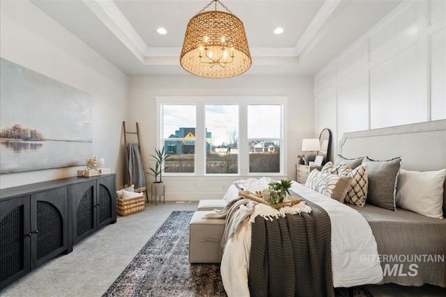 carpeted bedroom with a chandelier, a tray ceiling, a decorative wall, and recessed lighting